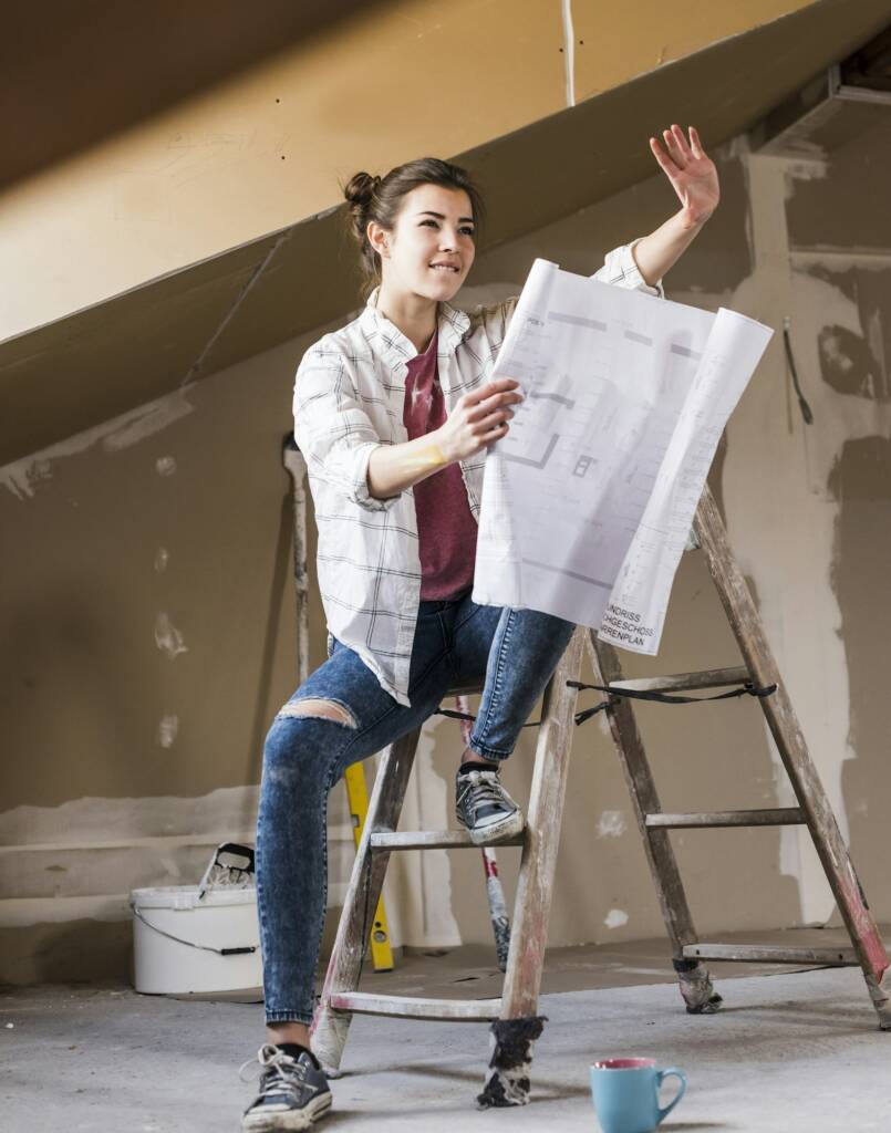 Young woman renovating her new home, holding construction plan